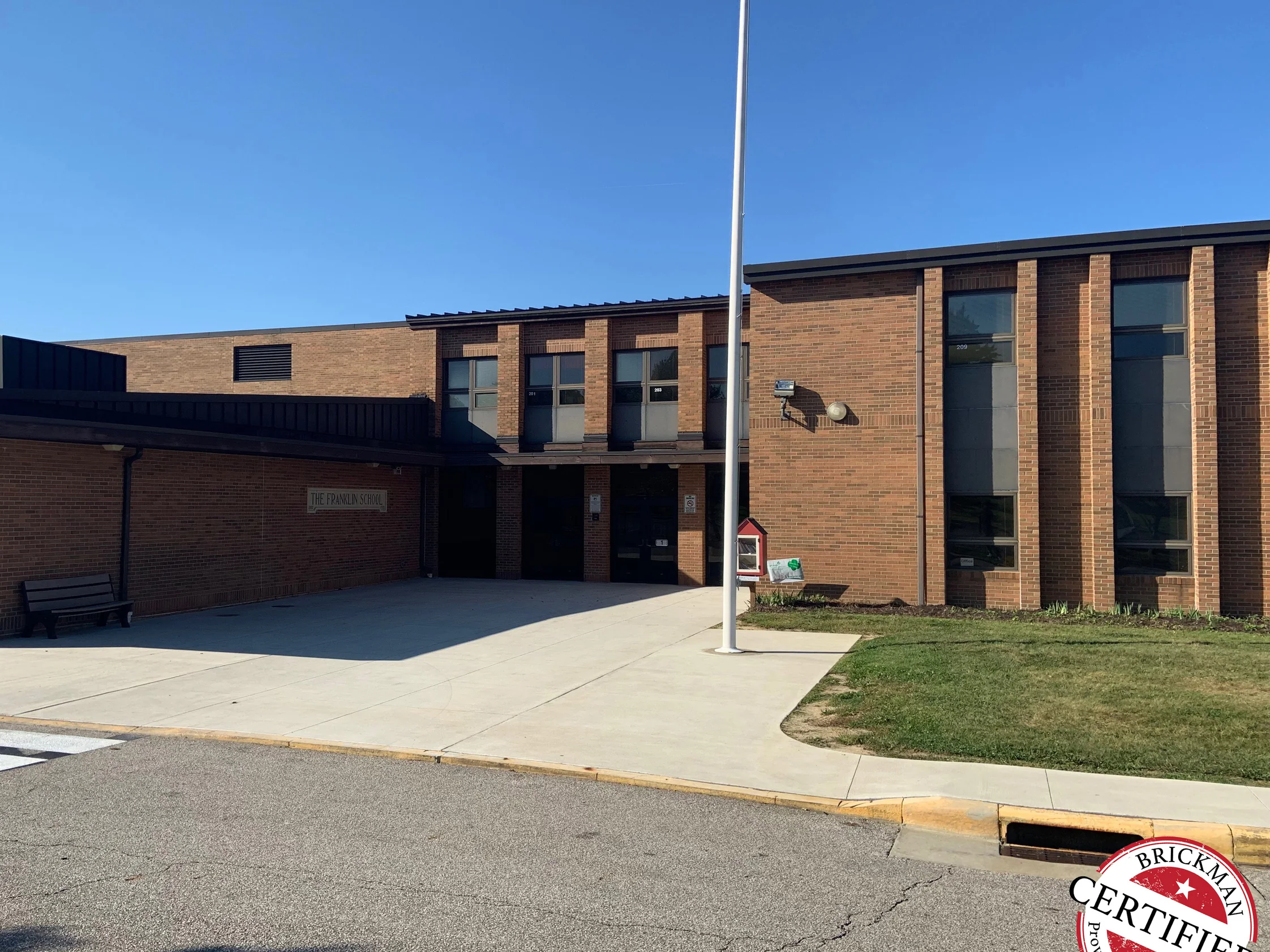 The front of the school in 2019 from the kerb, the two story classroom wing and the low entrance range reading as one even red brown brick