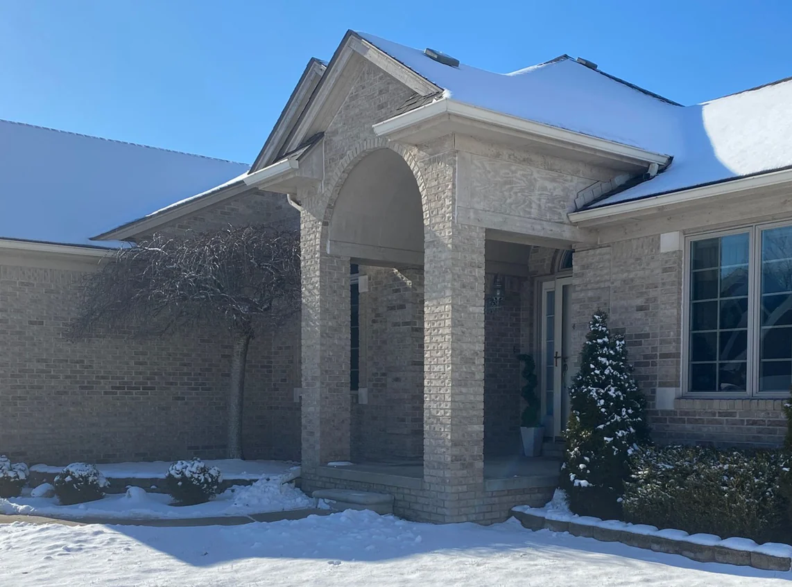 A Fraser, Michigan home under fresh snow in 2021, its light brick one even range twenty-three years after staining