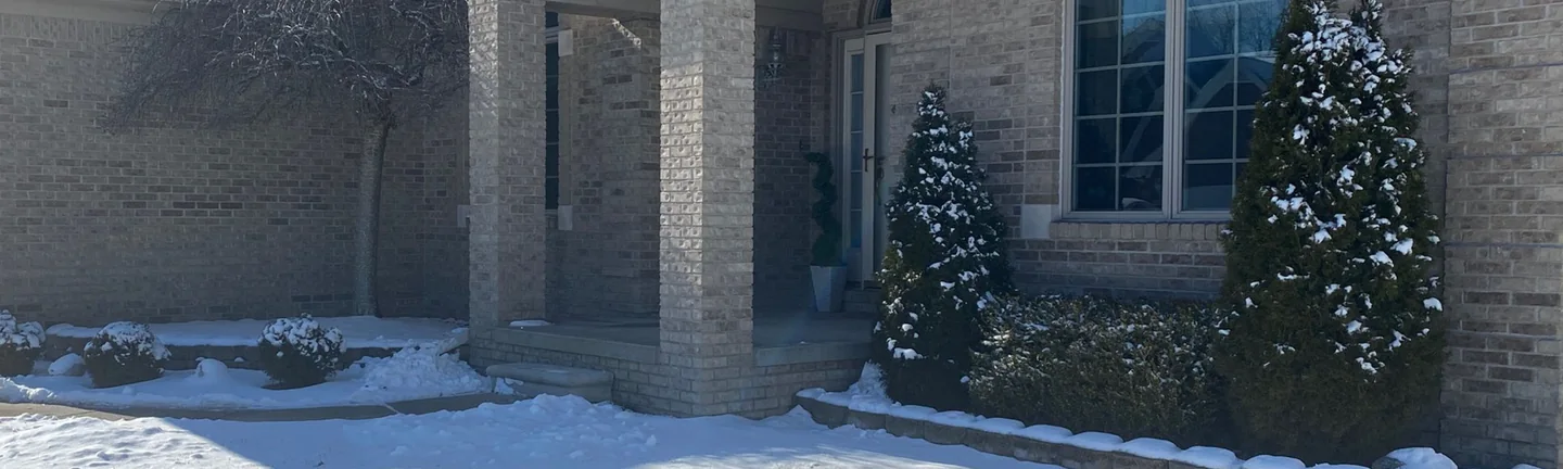 The front of the Fraser, Michigan home in 2021, its buff brick reading as one range across the entry piers and the walls either side