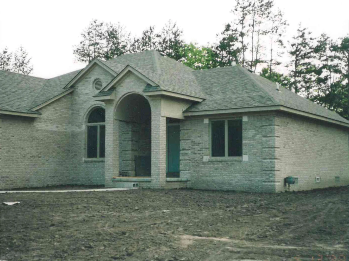The front of the single-story Fraser home in 1998 from the driveway, bare dirt in front of it, the buff brick showing lighter units mixed through the range