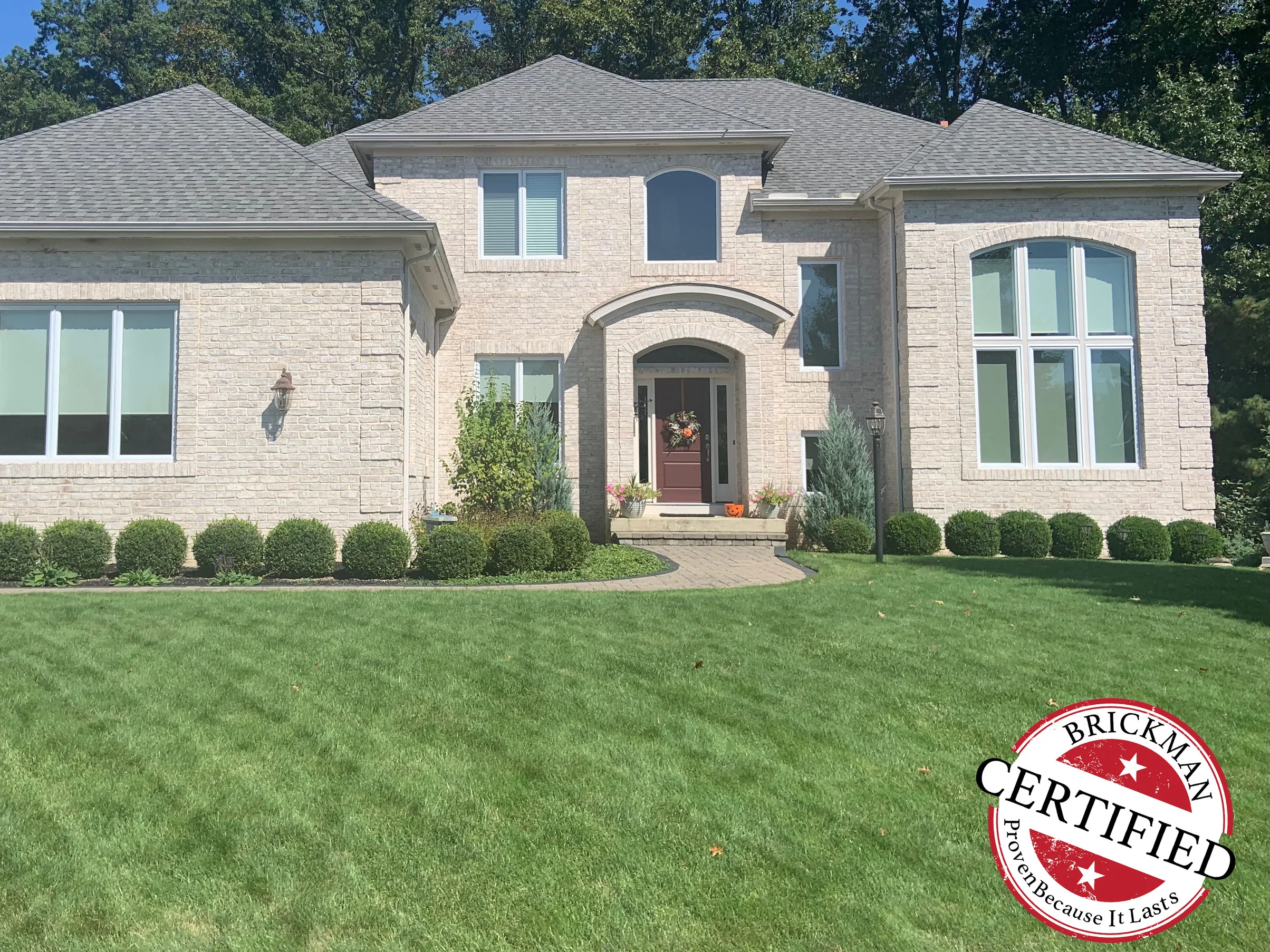 The front of the house from the lawn in 2019, the brick reading as one warm cream and buff range across the two-story centre and both wings