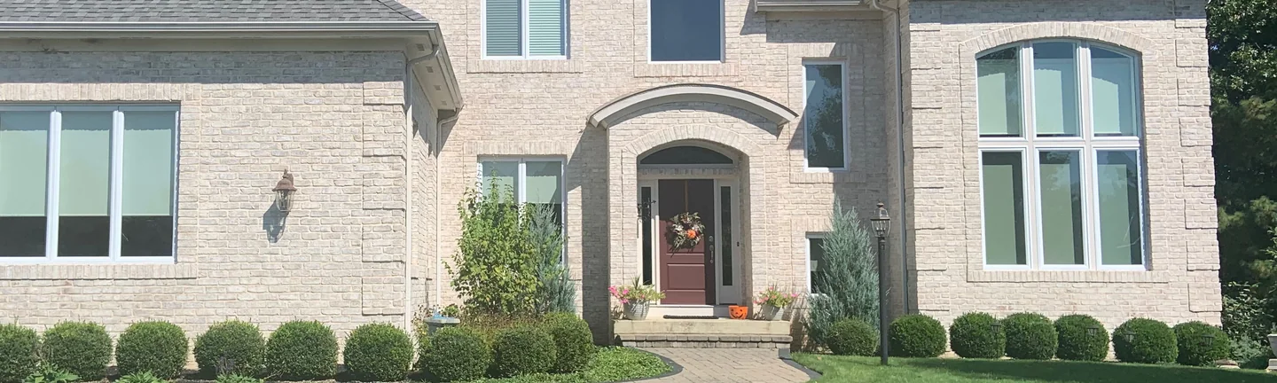 The brick front of a two-story home in 2019, reading as one warm cream and buff range across the wall