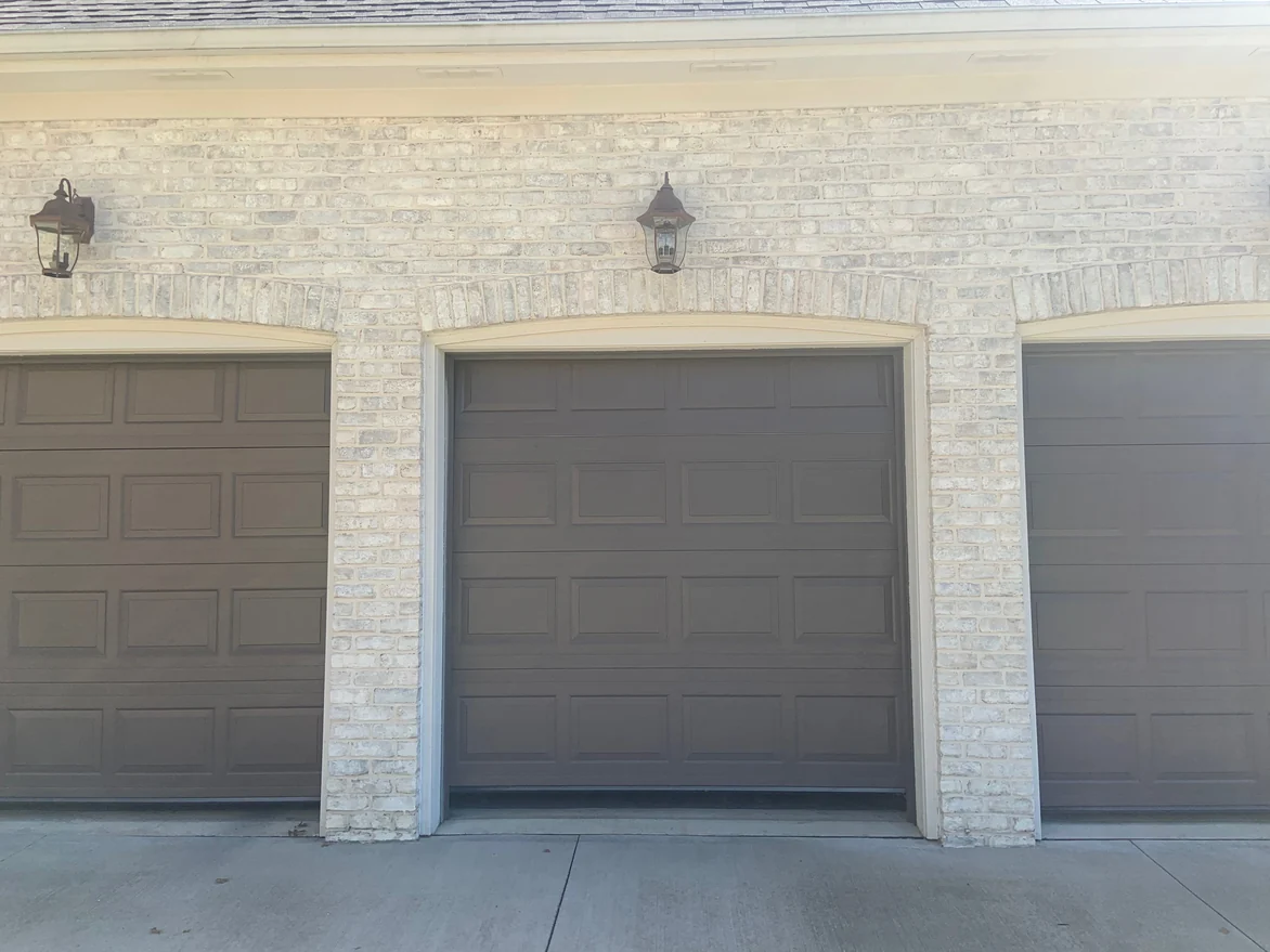 The garage openings in 2019, their segmental brick arches and carriage lamps above the driveway
