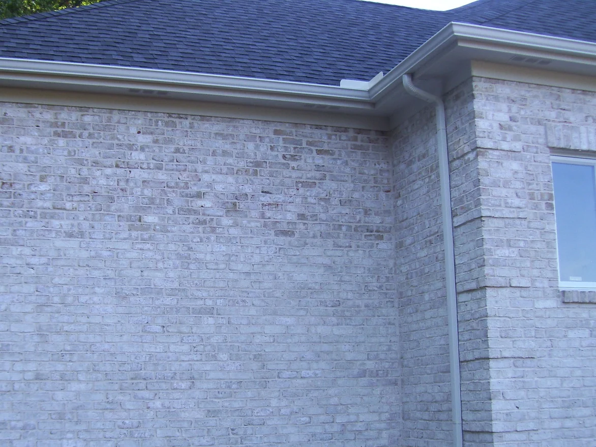 A blank side wall and outside corner of the house in 2011, the brick a flat chalky grey white from the ground to the eaves