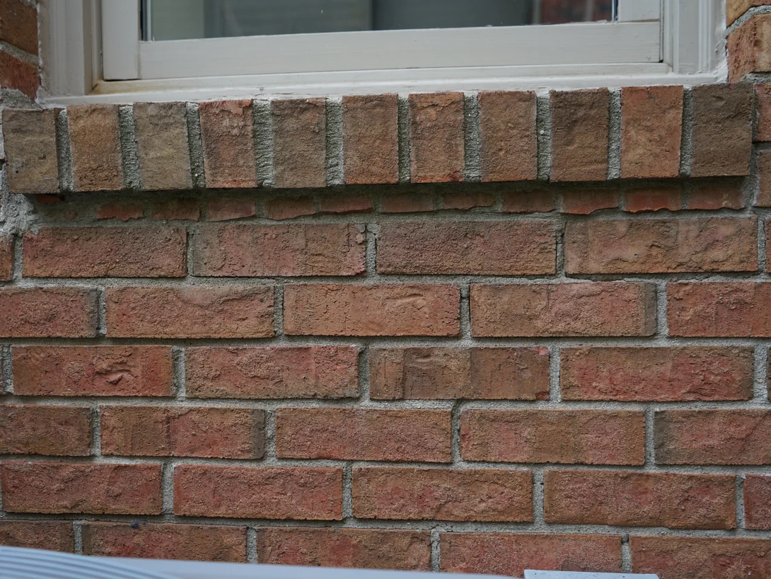 Close view of the brick under a rowlock sill in 2019, the units sitting in one range of tans and soft reds