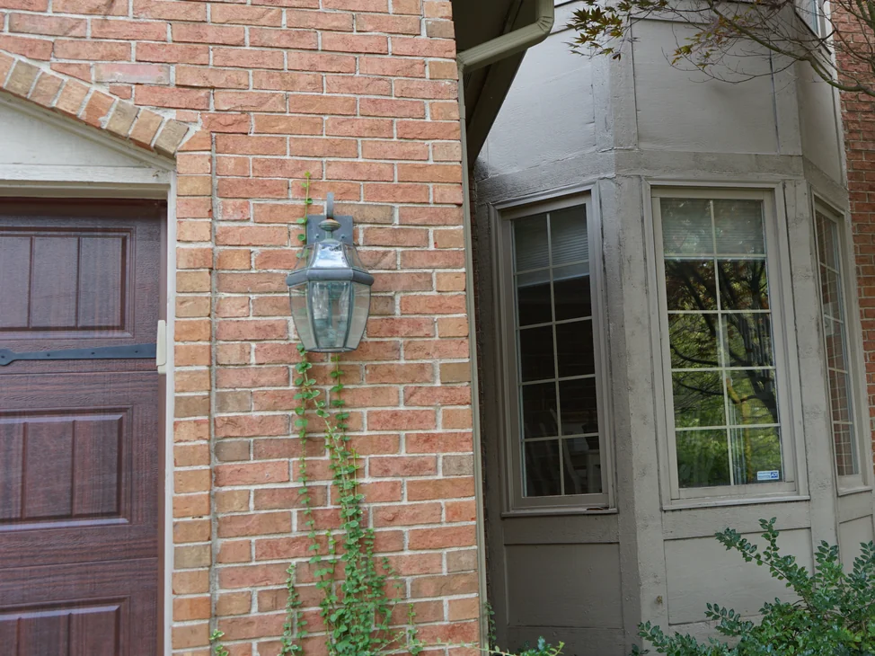 The garage bay and the bay window of the house in 2019, the brick reading as one even salmon and tan range.