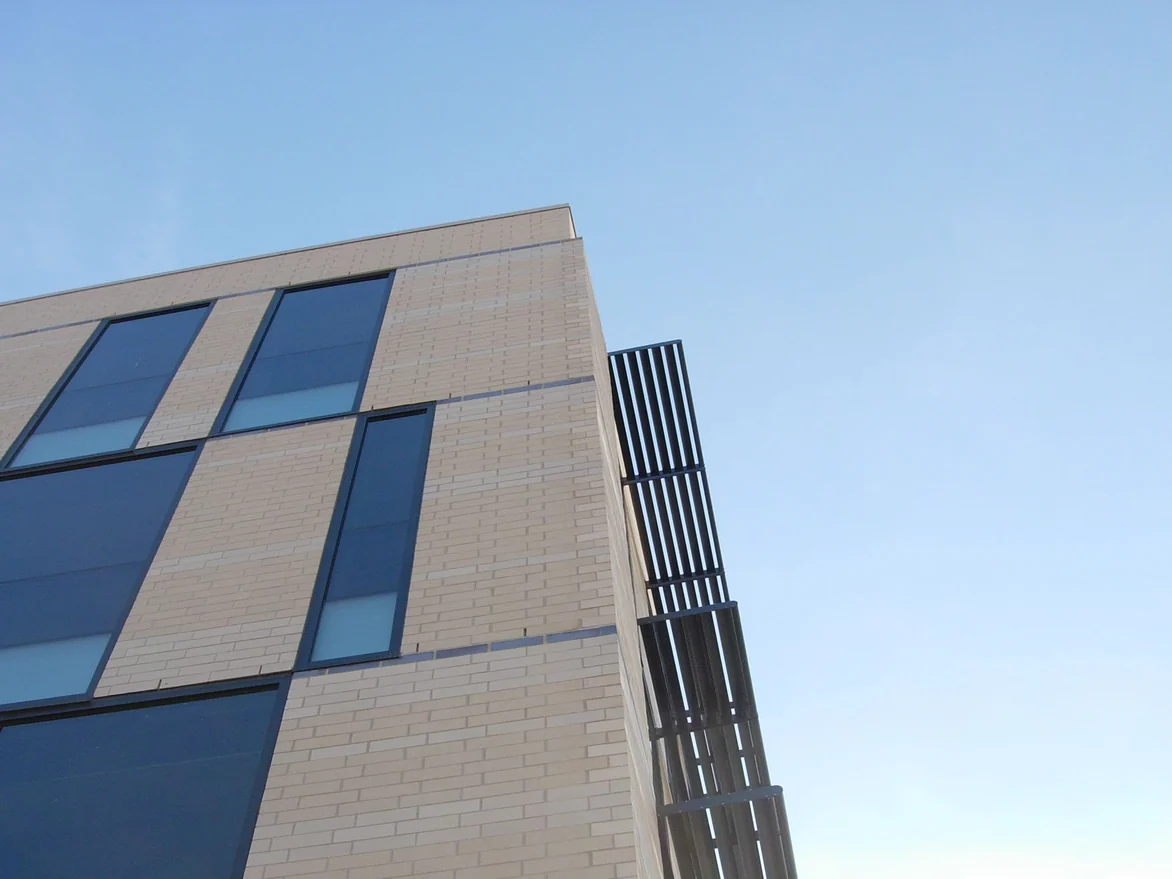 Looking up the corner of the four-story office in 2008, cream brick piers between bands of blue glazing with a metal sunshade fin at the corner