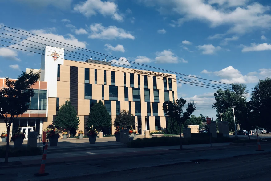 The four-story office from across the street in 2019, one cream brick elevation under the Diocese of Grand Rapids lettering