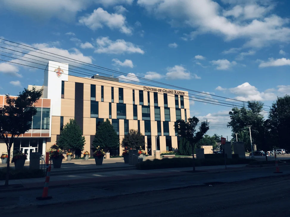The four-story office from across the street in 2019, one cream brick elevation under the Diocese of Grand Rapids lettering.