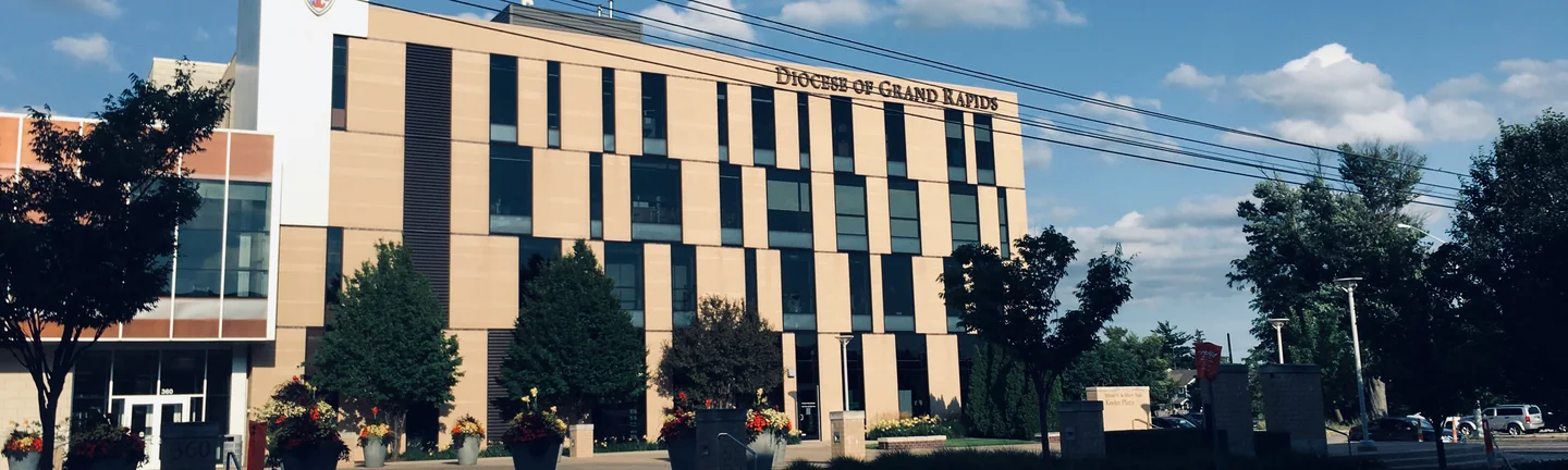 The four-story office from across the street in 2019, one cream brick elevation under the Diocese of Grand Rapids lettering