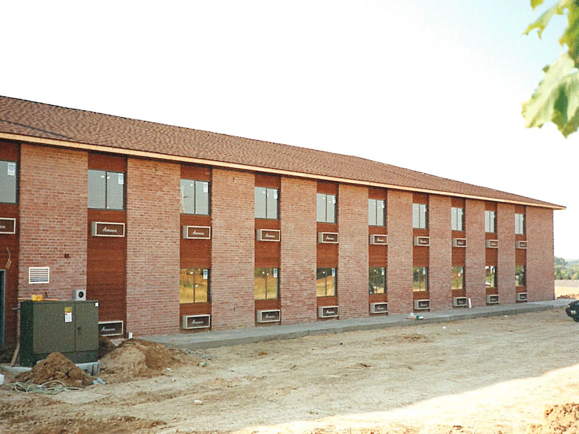 The long elevation of the hotel in 1997 on bare graded ground, its brick running in patches of pale pink and dark red between the window bays