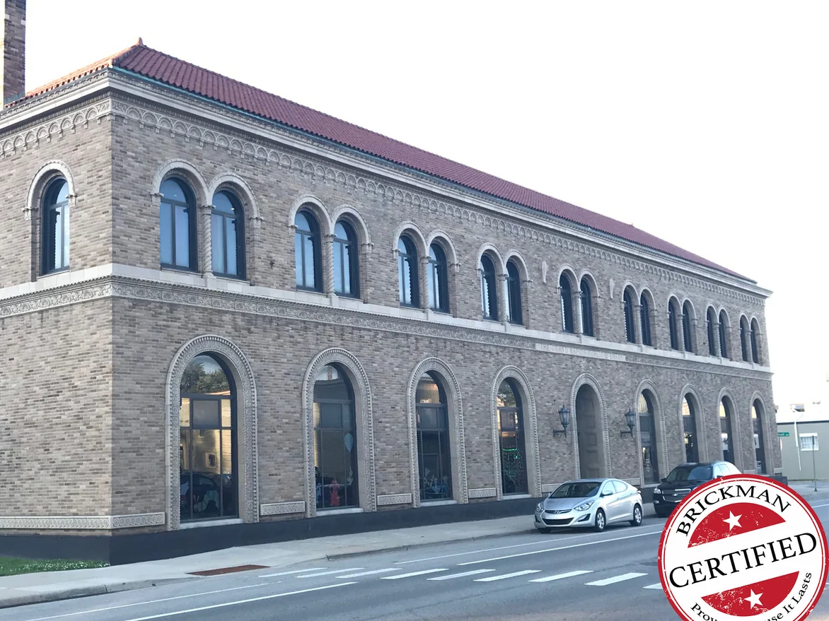The same corner of the library in 2019, carrying the Brickman Certified stamp, its brick reading as one even wall