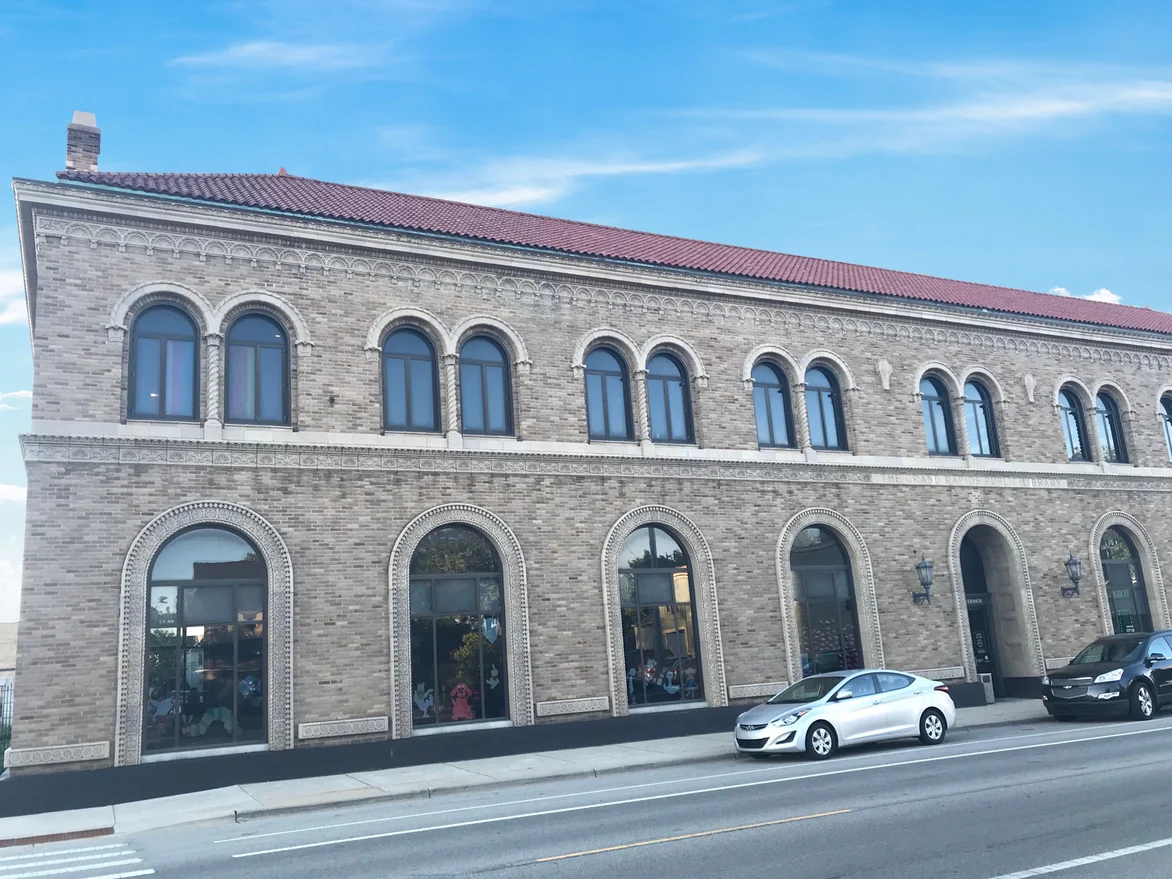The library's long elevation in 2019, its arched openings and carved band course set in evenly blended buff brick
