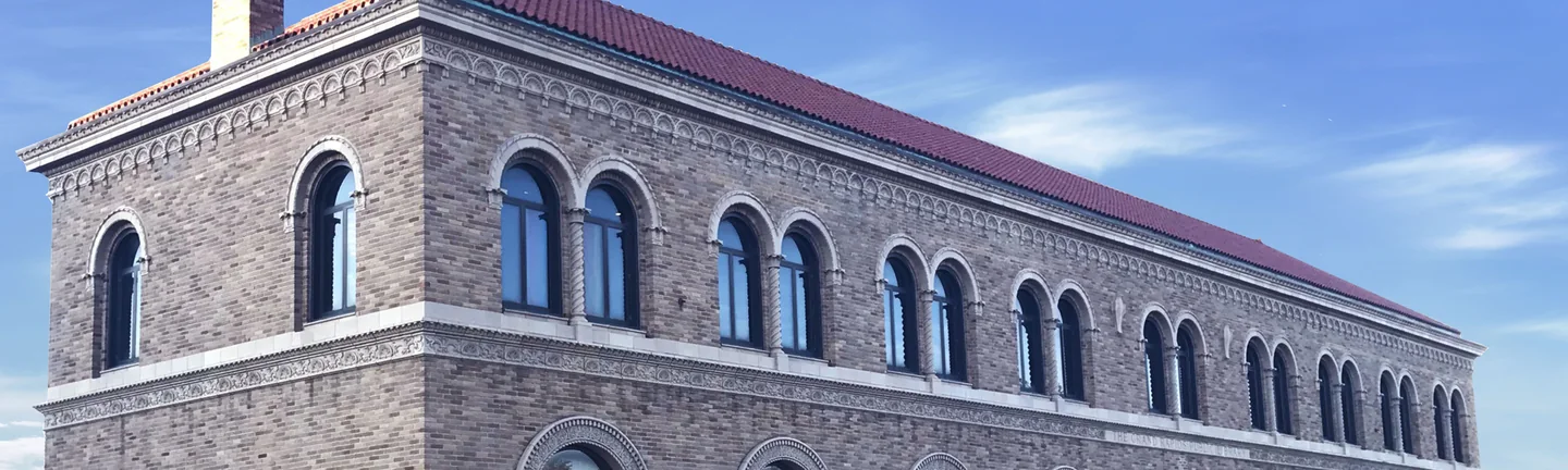 The upper storey of the Grand Rapids Public Library in 2019, an arcade of round-arched windows in evenly blended buff brick under a clay tile roof