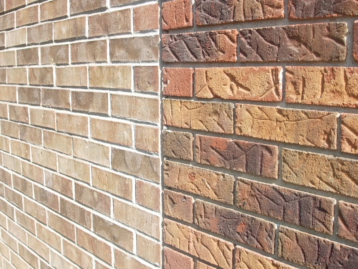 Two brick runs meeting at an outside corner in 2008, a smooth tan brick with pale joints on the left and a rougher, darker textured brick with grey joints on the right