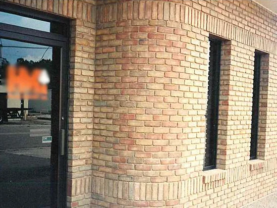 The glass entry door and a curved brick corner in 1994, the radial shape brick on the curve reading pinker than the tan face brick beside two narrow windows