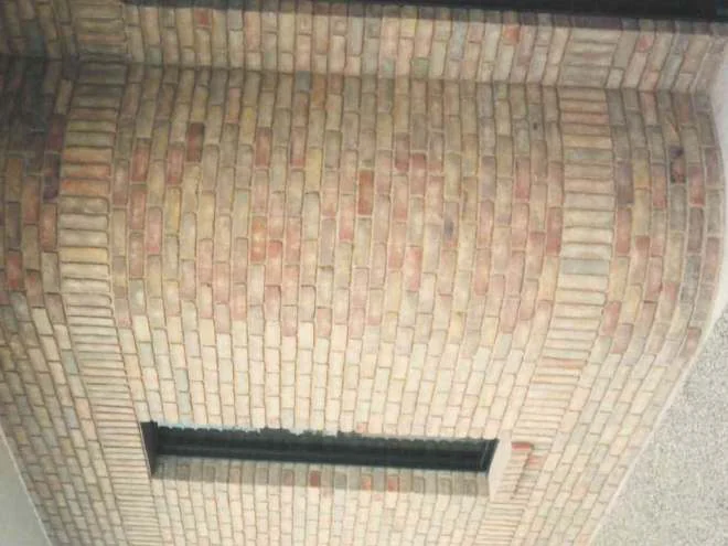 Looking up at a curved brick bay in 1994, a tall narrow window on its left face and the radial shapes on the curve a shade redder than the flat wall