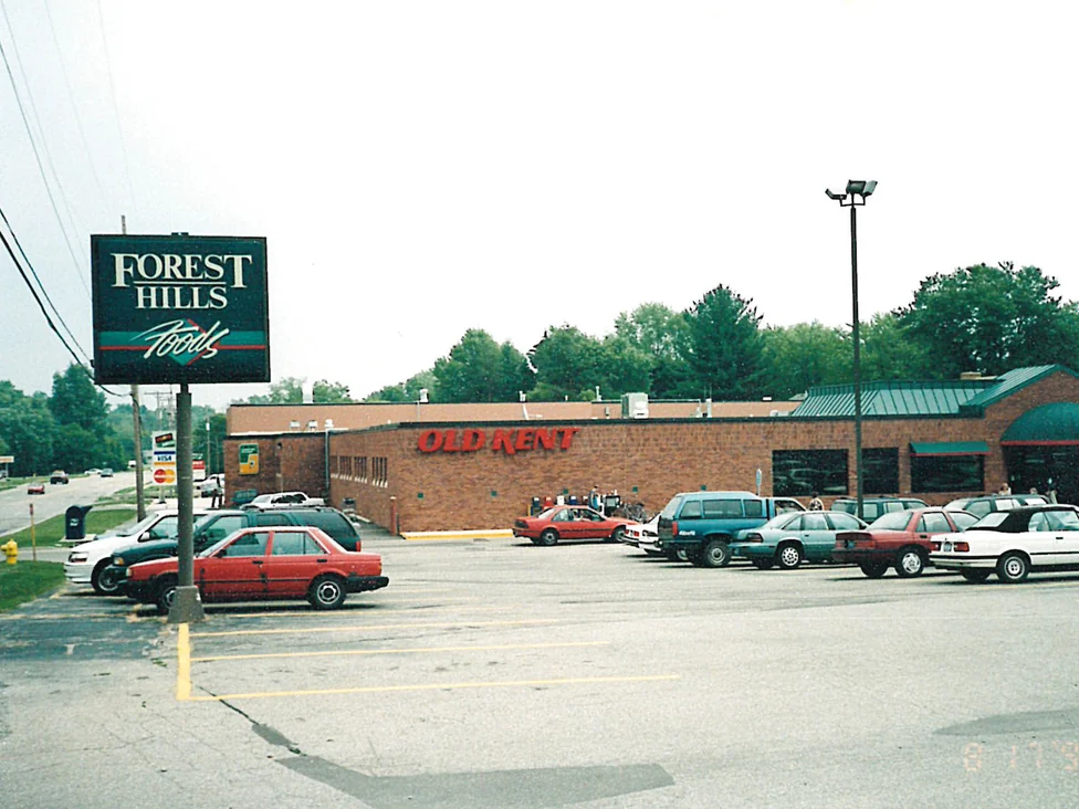 The store from across its parking lot in 1998, a Forest Hills Foods pylon sign at the kerb and one run of red brick along the front under a green roof