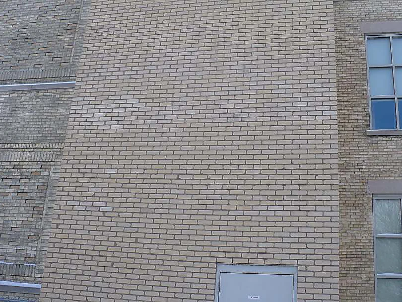 The shaft in 2002 after the dark brick was lightened, its face reading as one pale range beside the older tan brick and a window bay