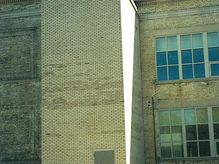 The new elevator shaft in 2002 before staining, bands of darker brick running through the courses across its face, with the older school and two rows of windows at the right