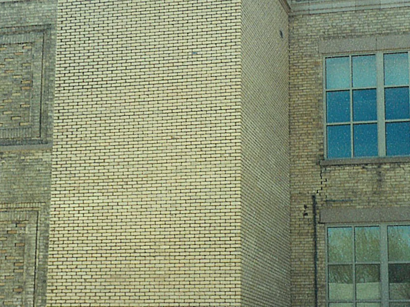 The shaft in 2019 with snow on the ledges, its brick one even light range from the door to the top of the frame, older patterned brickwork at the left and two windows at the right