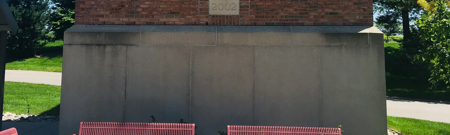 The brick column on the university campus in 2019, its 2002 date stone set in salmon red brick above a cast stone base