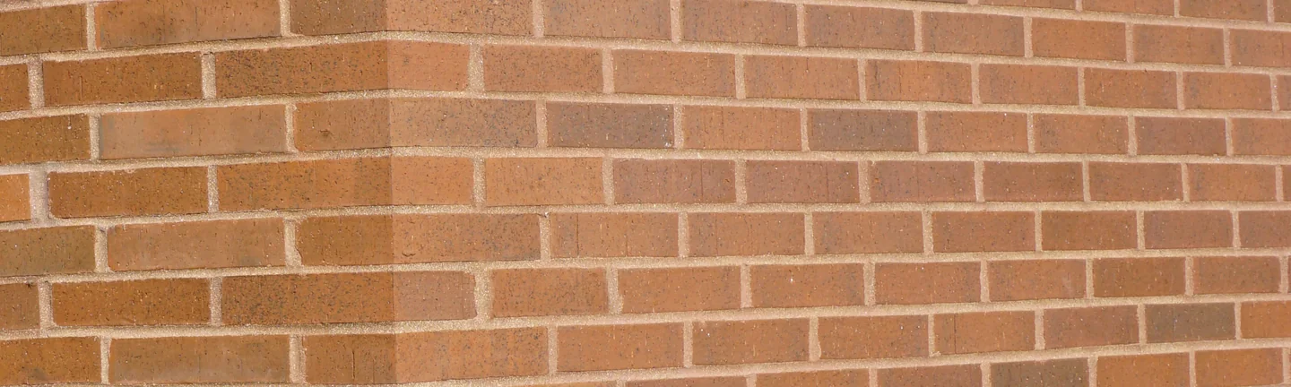 The brick at an outside corner of the library in 2019, the shaped corner units reading as one range with the walls either side of them