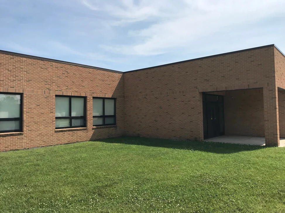 Two wings of the school meeting at an inside corner in 2019, the brick reading as one red and tan blend across both walls
