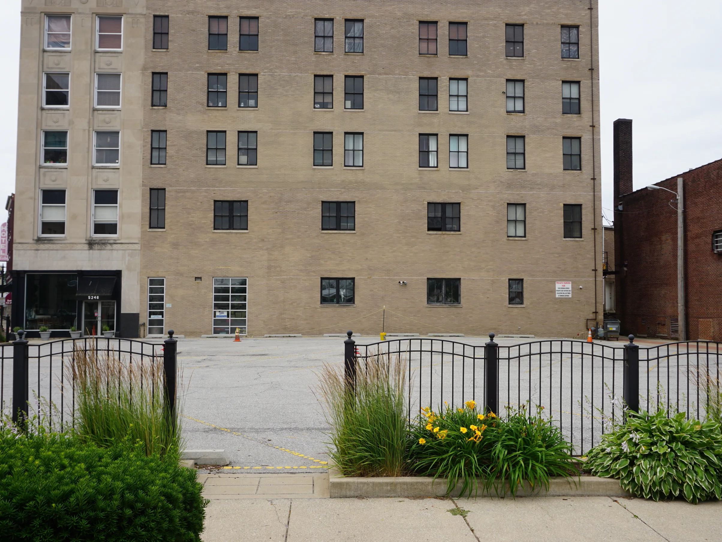 The building in 2019 from across its parking lot, the main wall and the limestone corner tower with the storefront and the neighboring block beside them