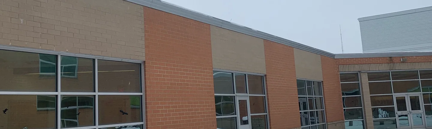 The high school courtyard in 2021 under snow, tan panels above each window bay set between piers of orange brick