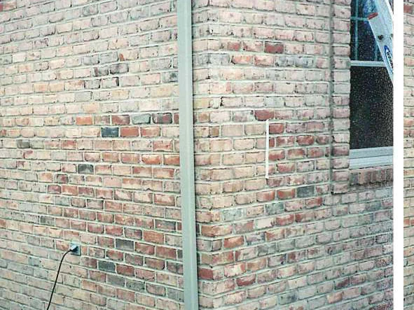 An outside corner of the house in 2000 with a downspout on the arris, a ladder at the right and a camera date stamp of 11 12 00 in the corner