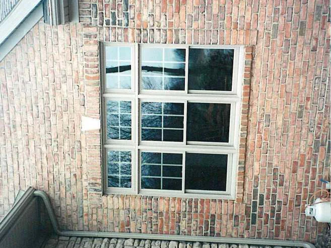 The same three-part window in 2000 after the correction, the brick under the sill reading as one range with the wall, a downspout at the left