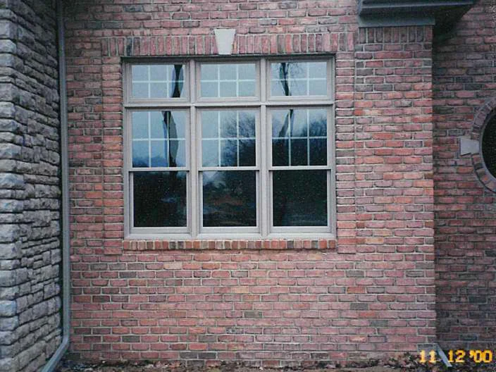 A three-part window in the red brick wall in 2000, with a run of darker off color units under the sill at the left and a camera date stamp in the corner
