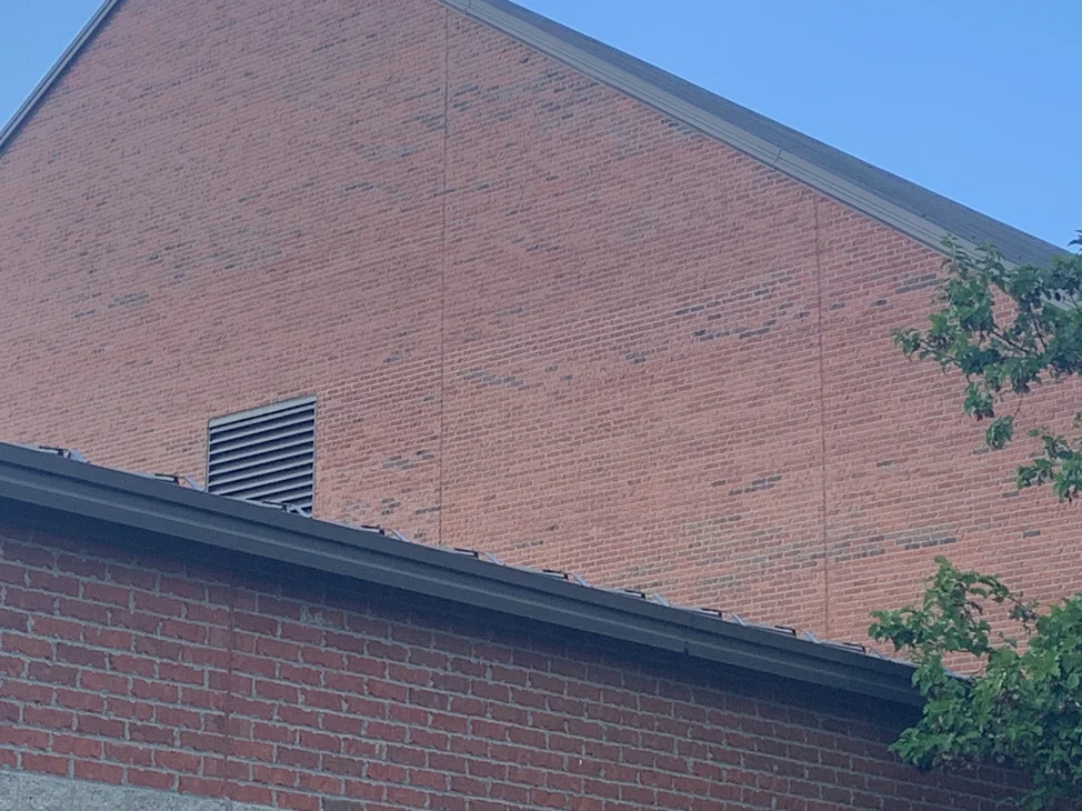 The full gable end of the Hilliard church in 2019, its brick one even orange range from the louvred vent up to the roof line, above the darker brick of the wing in front.
