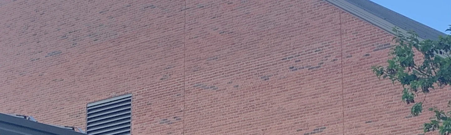 The stained gable wall of the Hilliard church in 2019, its brick reading as one even orange range around a louvred vent