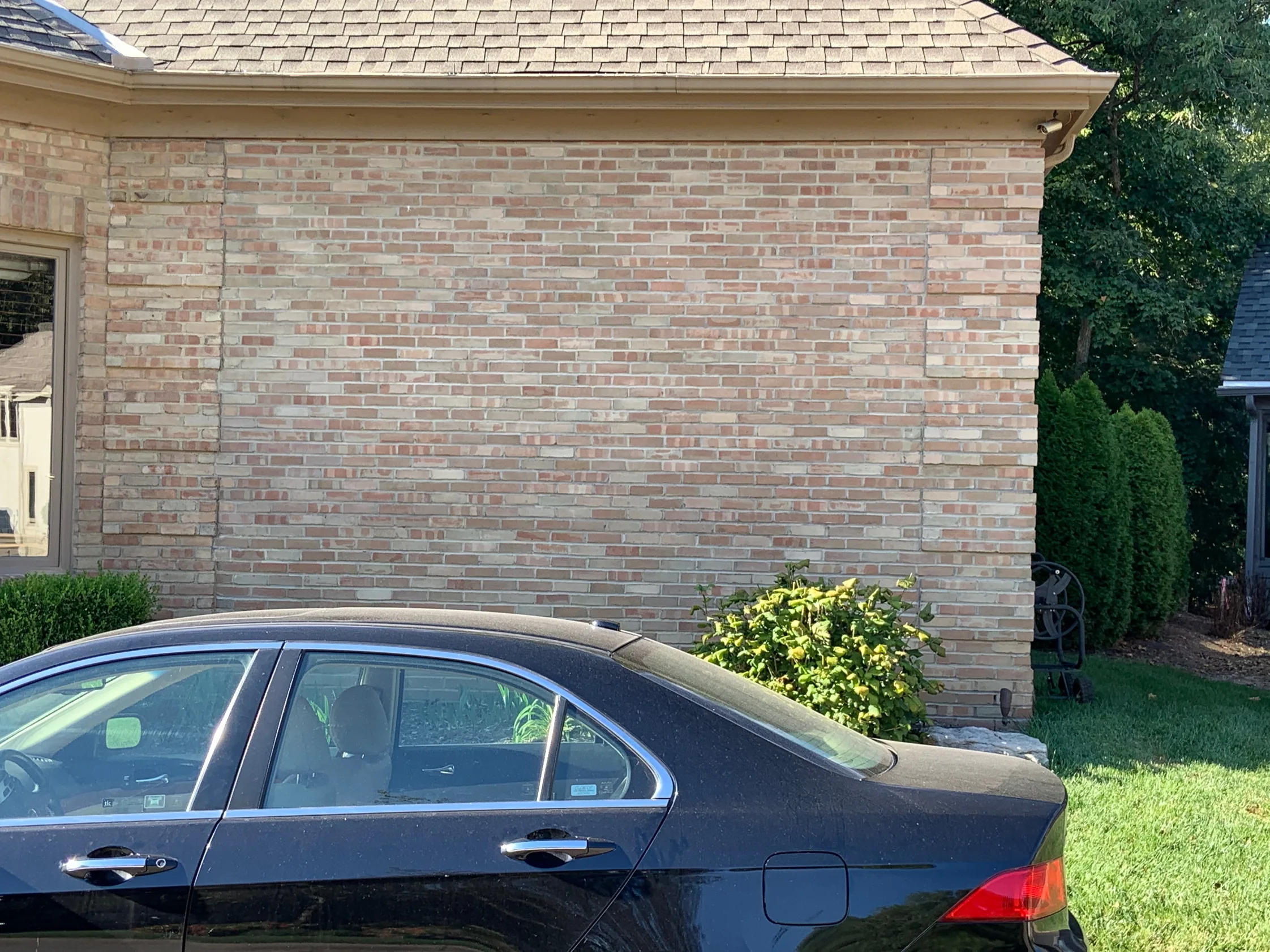 The addition wall in 2019, photographed from the same side as the period frames, its brick an even buff, rose and cream mix from the sill course to the eaves