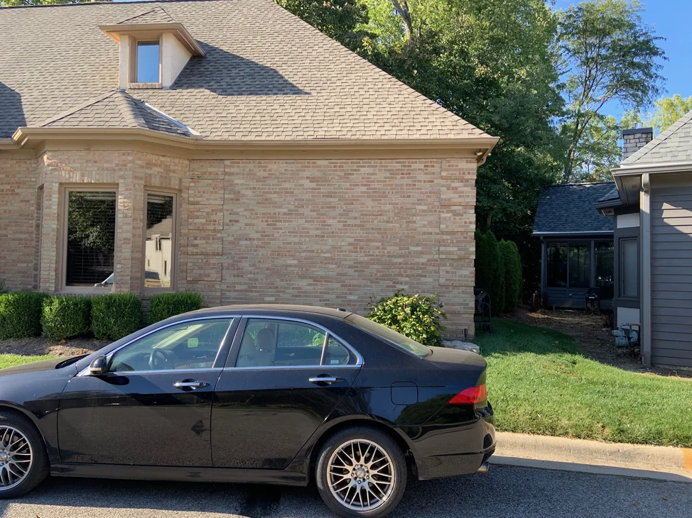 The house seen from the kerb in 2019, the hipped roof and dormer above a long brick elevation that reads as one buff and rose range across its whole length.