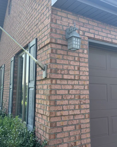 The corner of a house in Hillsboro, Ohio in 2019, its brick one even range sixteen years after staining