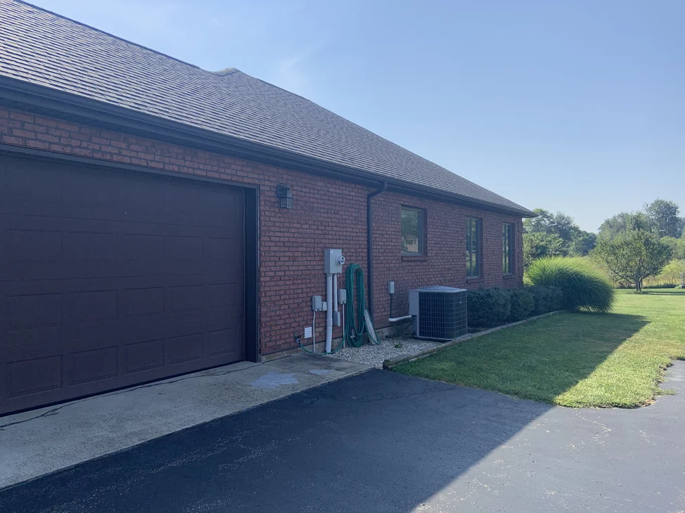 The house from the driveway in 2019, the garage wall and the wing beyond it reading as one red and tan range at distance.
