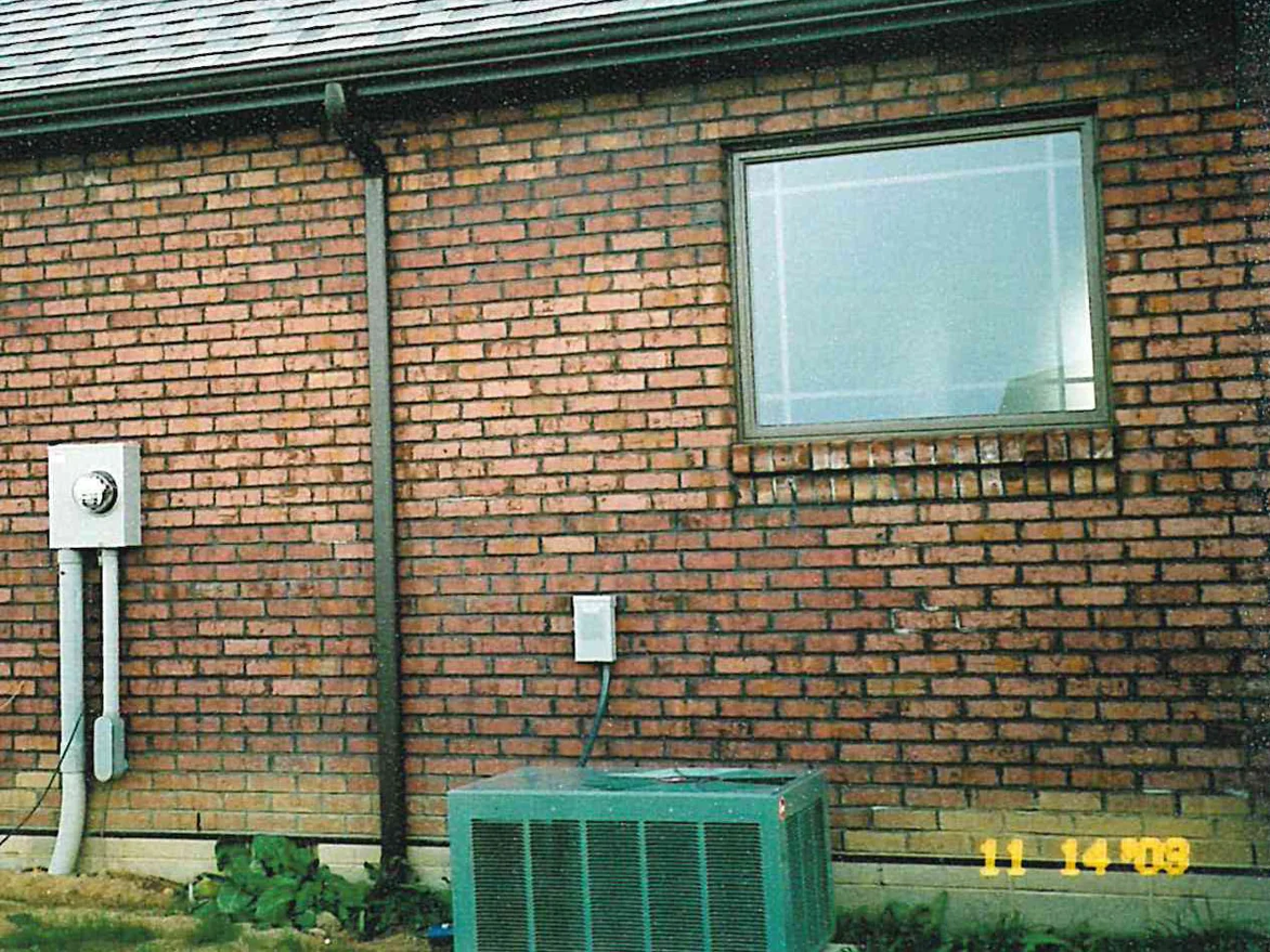 A side wall of the house in 2003, dark brick running in patches under the window head and along the courses beside it