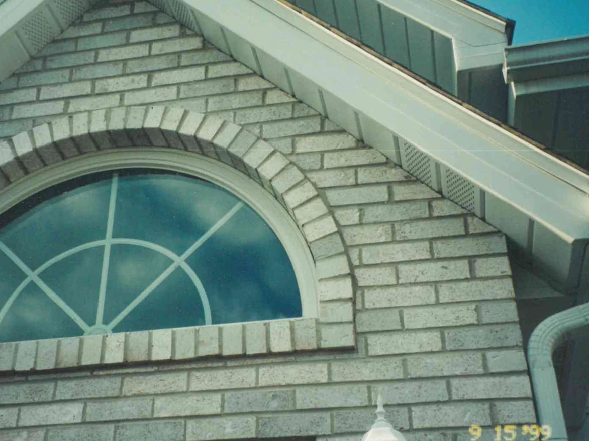 The gable above the entrance in September 1999, the arched transom and the grey brick around it reading as one blend, with the camera's date stamp in the corner
