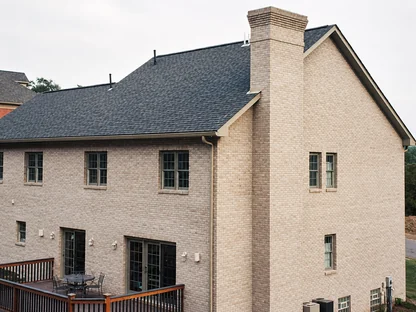 The rear elevation of a large house, the brick one even cream color across two storeys and the chimney