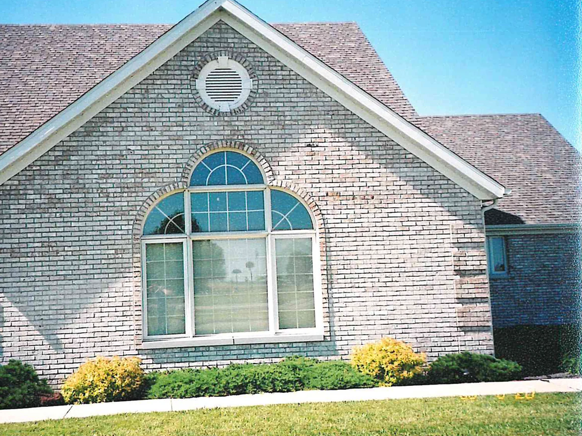 The front gable in 2003, a round louvered vent above an arched window and the brick around them reading as one cream and grey range
