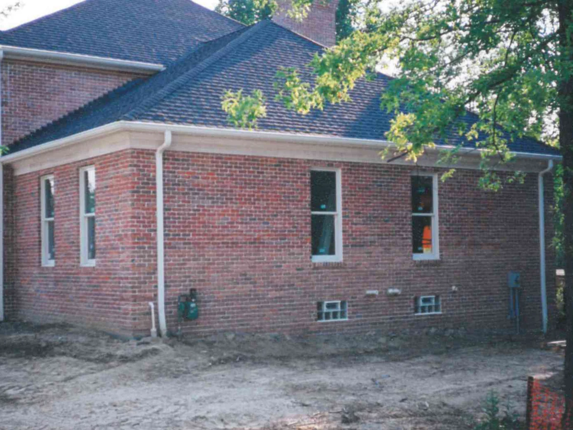 The outside corner of the house in 1997 while the work was underway, red brick with scattered darker units and bare dirt still around the foundation