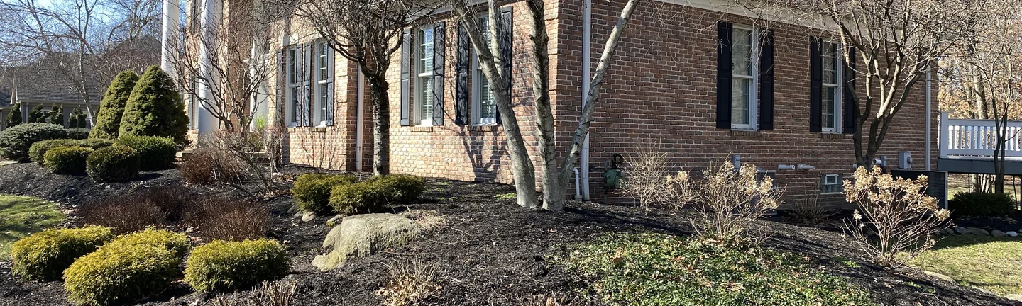 The house in 2021 seen from the front corner, red brown brick running the length of the side elevation to a chimney on the ridge and a white portico at the far end