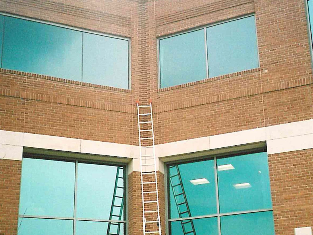 An inside corner of the building in 2005, an extension ladder run up the brick pier between two tall window bays to the banding at the top
