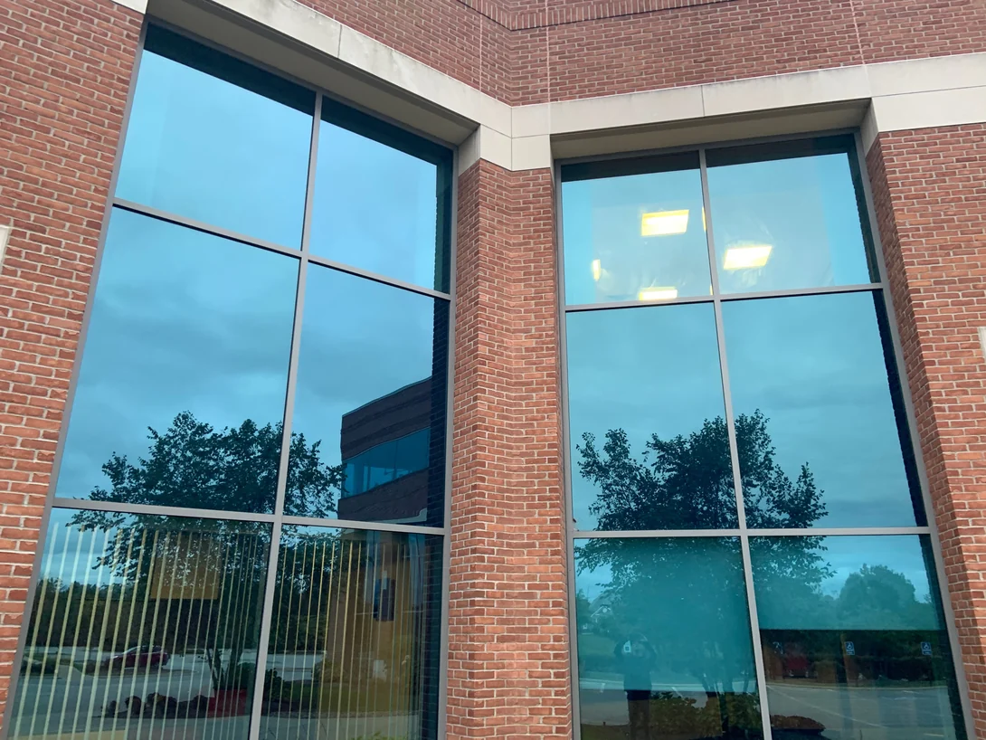 Two ground floor window bays either side of a brick pier in 2019, the brick one range from the cast stone band above them down to the sill