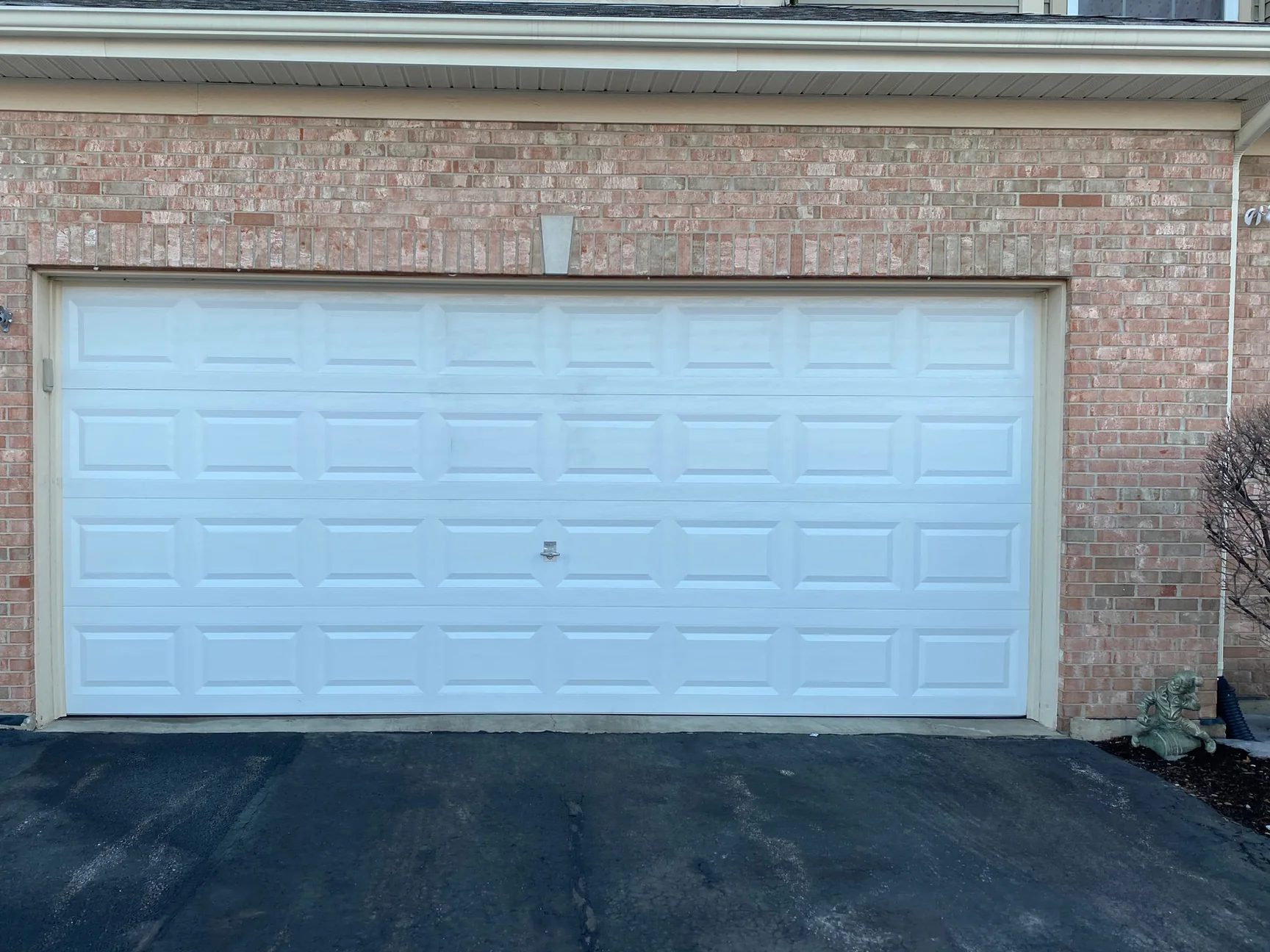 The next garage bay along the row in 2021, the end-set course over the door head reading with the field brick, a pale cast stone wedge at the centre of the opening
