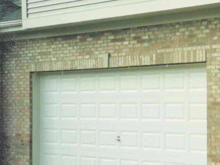 The garage bay in 2002, a course of pale brick set on end across the head of the opening against the tan and cream wall around it