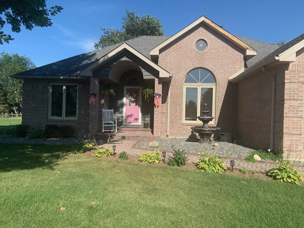 The front of the house in 2019, the entry set under a brick arch beside a tall arched window, the brick one pale range.